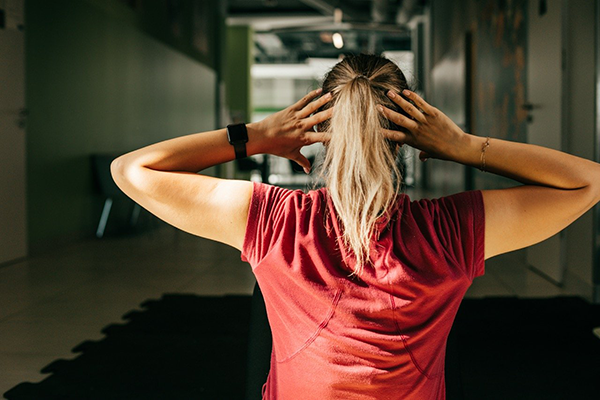 Maddie standing in a gym hallway, hands on head